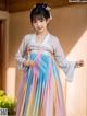 A young girl wearing a colorful hanbok standing in front of a window.