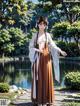 A woman in a long dress standing in front of a pond.