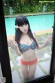 A woman in a bikini standing in front of a window.