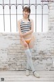 A woman in a striped tank top and white stockings posing for a picture.