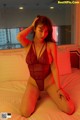 A woman in a red lingerie sitting on a bed.