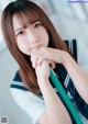 A young woman in a school uniform holding a green pencil.