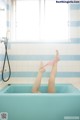 A woman laying in a bathtub with her feet up in the air.