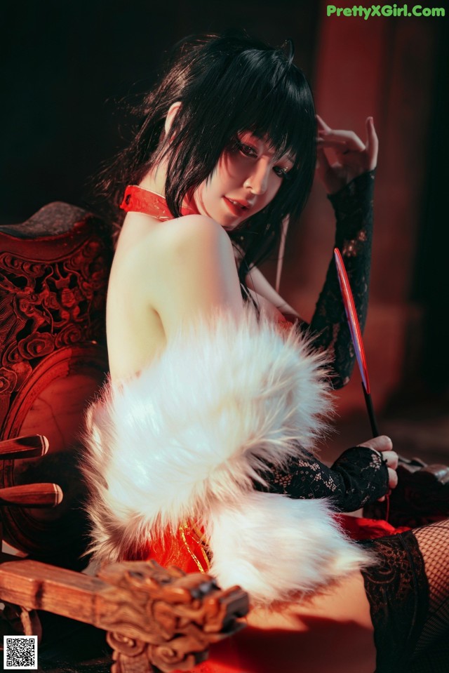 A woman in a red dress sitting on a chair holding a sword.