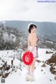 A woman in a pink dress holding a red heart in the snow.