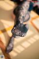 A woman in black fishnet stockings sitting on a tatami mat.