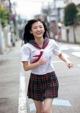 A young woman in a school uniform running down the street.