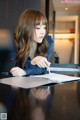 A woman sitting at a table writing on a piece of paper.