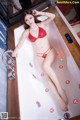 A woman in a red bikini sitting in a bathtub.