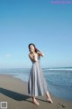 A woman standing on a beach next to the ocean.