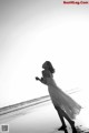 A woman in a white dress is walking on the beach.