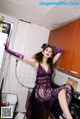 A woman in a purple dress sitting on a kitchen counter.