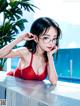 A woman in a red bathing suit sitting by a pool.