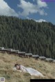 A woman laying on top of a grass covered hillside.