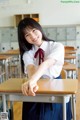 A young woman sitting at a desk in a classroom.