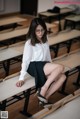 A woman sitting on a bench in a classroom.