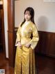 A woman in a yellow kimono standing in a room.