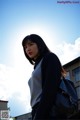 A woman with a black bag standing in front of a building.