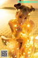 A young girl sitting on a bed covered in fairy lights.